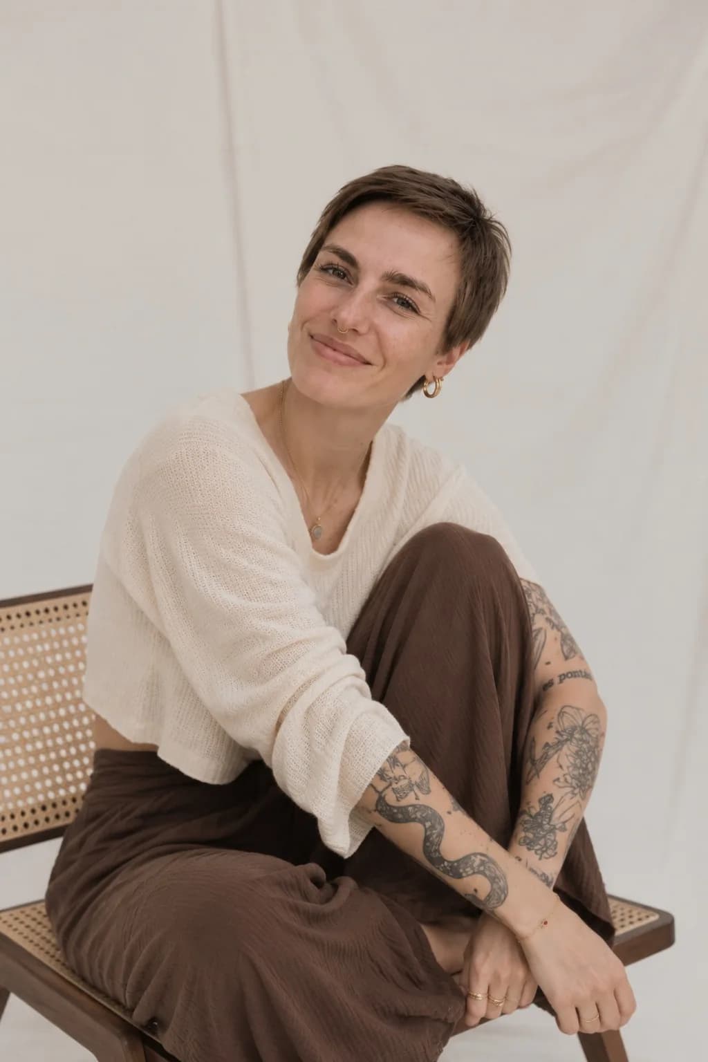 Hannah sitzt lächelnd mit angezogenem Bein