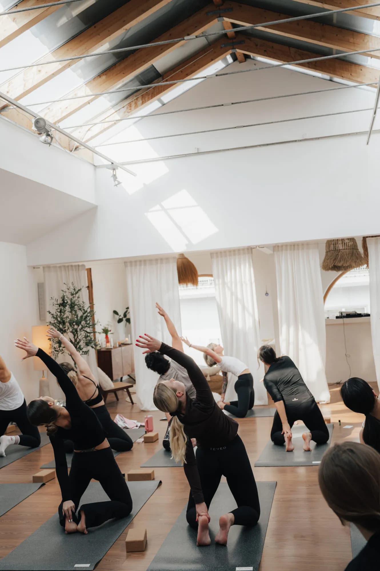 Yogaklasse in einer seitlichen Dehnung unter dem Dachfenster